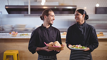Happy hospitality staff showing food
